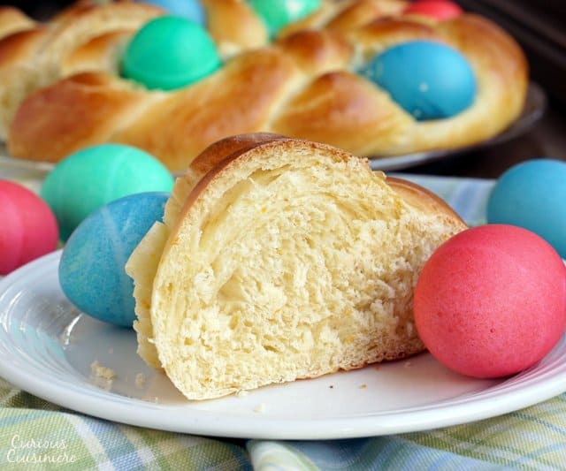 一片意大利复活节面包(Pane di Pasqua),周围是染色的复活节彩蛋。| www.CuriousCuisiniere.com