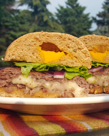 一个多汁的汉堡塞满了粘稠的奶酪是任何夏季烧烤或烧烤的完美补充。把烤架生火!