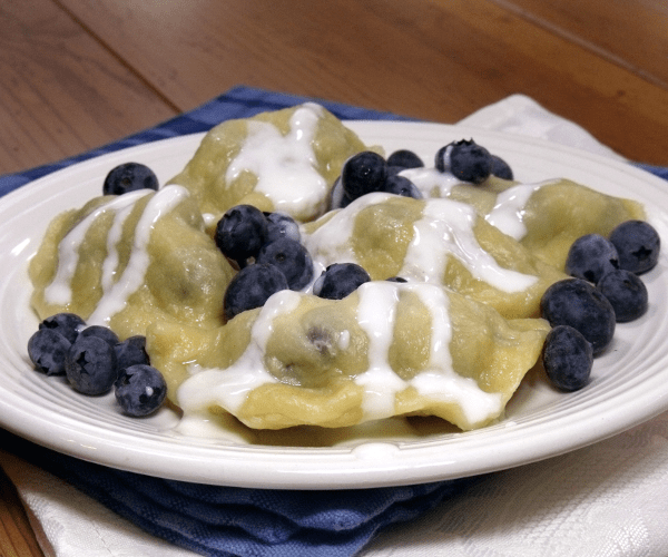 一种传统波兰pierogi的甜点,里面有蓝莓,上面有甜奶油。
