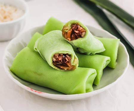 Kueh dadar是一种色彩鲜艳的东南亚小吃。图片中绉被打开，可以看到填充。| www.CuriousCuisiniere.com