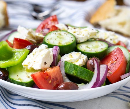 一碗正宗的希腊沙拉(Horiatiki)的特写镜头，一种不含生菜的厚实沙拉。夏季蔬菜，咸橄榄和奶油羊乳酪。