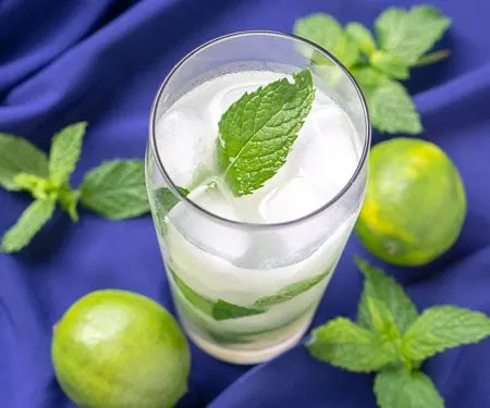 蓝背景古巴 莫吉托饮料加石灰和新薄荷叶薄荷、石灰和白朗姆酒网站CuriousCuisire.com