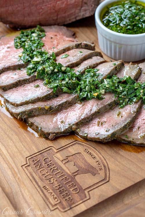 切的顶面烤烤肉用chimichurri调味汁在一个认证的安斯牛肉品牌烙画的木切板。