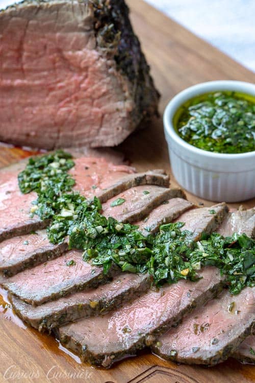 切的顶部圆形烤牛肉用chimichurri调味汁。一个完美的假日烤配方。